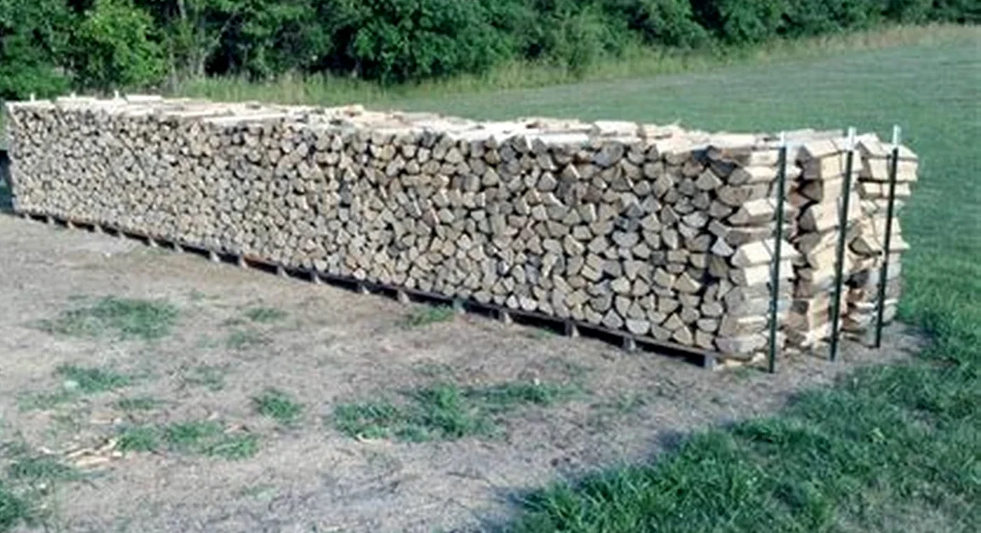 Real split firewood stored outdoors with airflow around the stack.