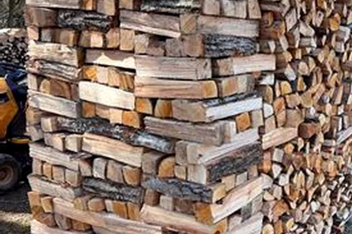 Close documentary detail of split firewood stacked in a substantial wall.