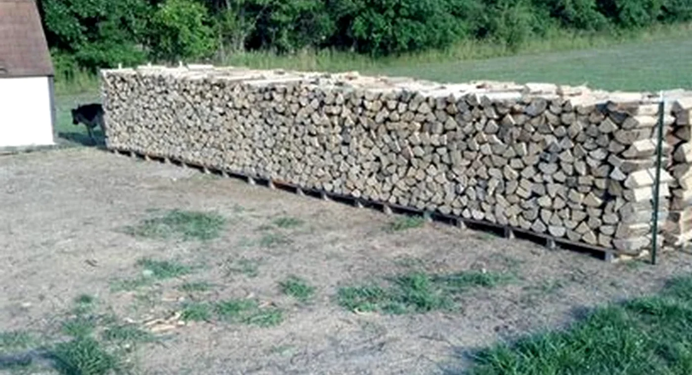A real long outdoor stack of split firewood used to illustrate measured quantities.